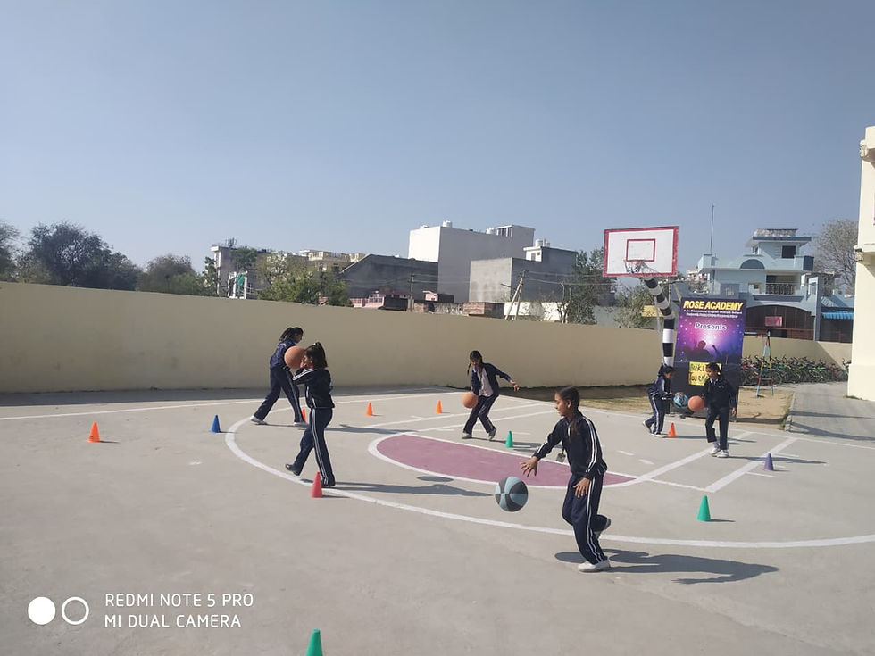 Students dribbling basketballs during outdoor practice on a bright sunny day.