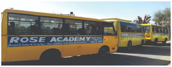 Yellow school buses for ROSE ACADEMY, Pratap Nagar Jaipur, parked outside.