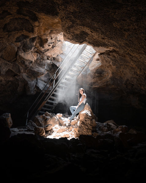 Woman sitting in a lava tube under the stairs in the light rays.