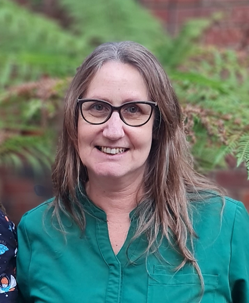 Nicole, Aged Care Graduate A photo of a women smiling, with dark hair, glasses and a green shirt.