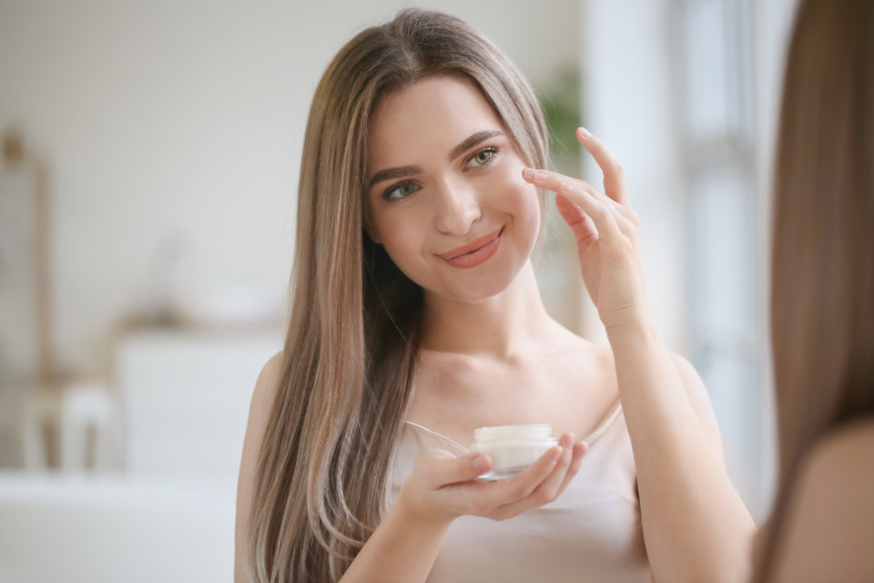Woman layering skincare products from lightest to heaviest