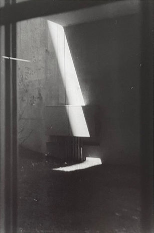 Photo of a shaft of sunlight shining onto a concrete wall and the ground
