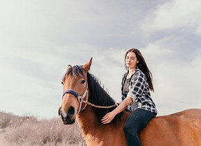 207823855-young-happy-woman-in-hat-with-her-horse-in-evening-sunset-light-outdoor-photogra