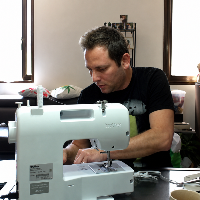 Designer sewing custom face masks late at night in a home workspace.