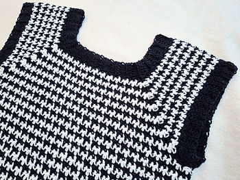 A white and black crocheted houndstooth crew neck vest