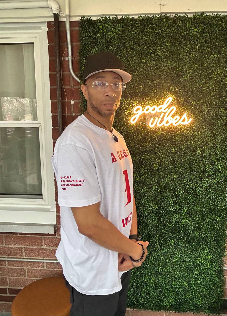 Malachi Muhammad wearing a red and write G.R.E.Y. shirt