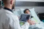medic-holding-digital-tablet-with-throat-mri-looking-sleeping-patient-hospital-bed-after-t