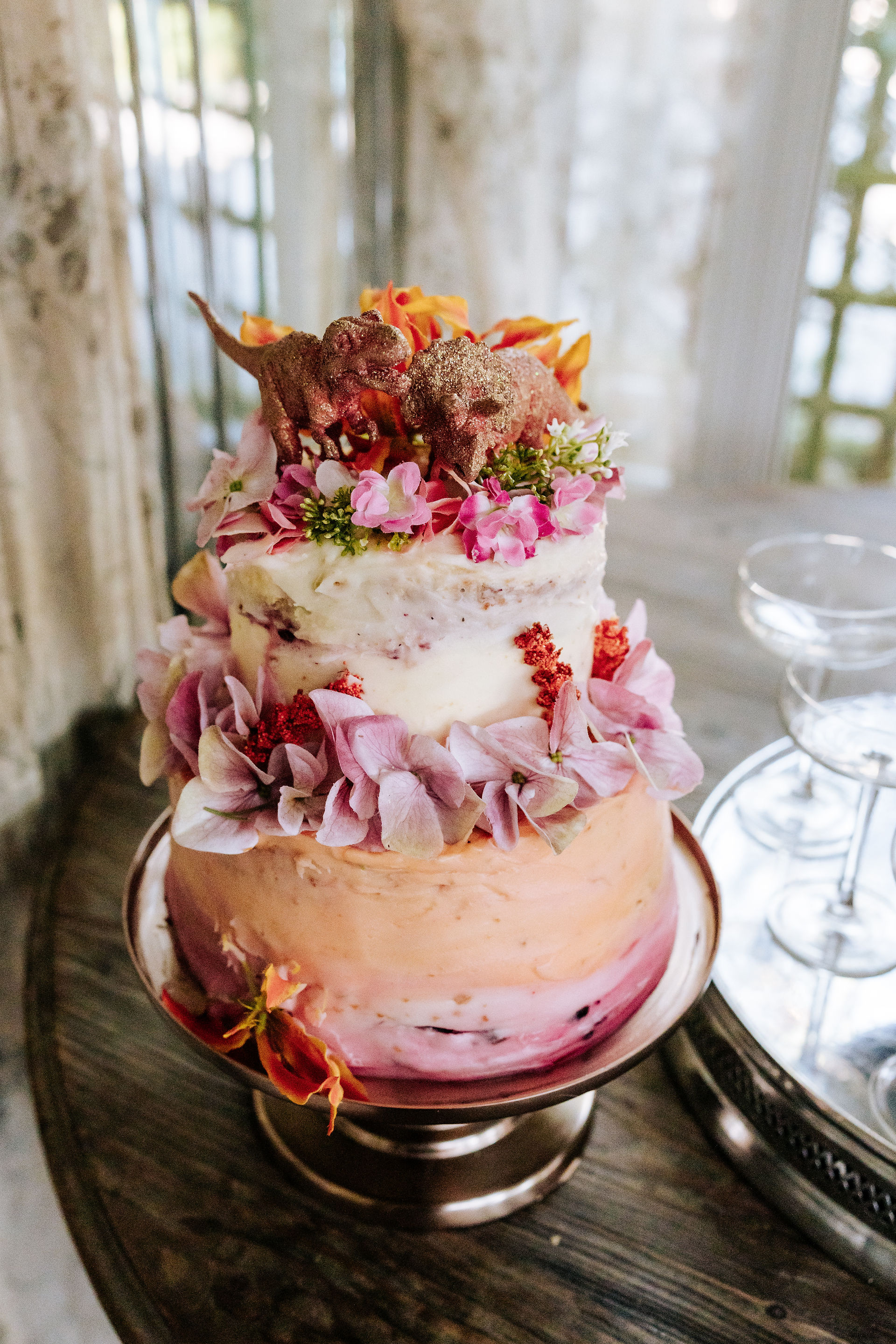 Pink and white wedding cake with dinosaur and floral topper 