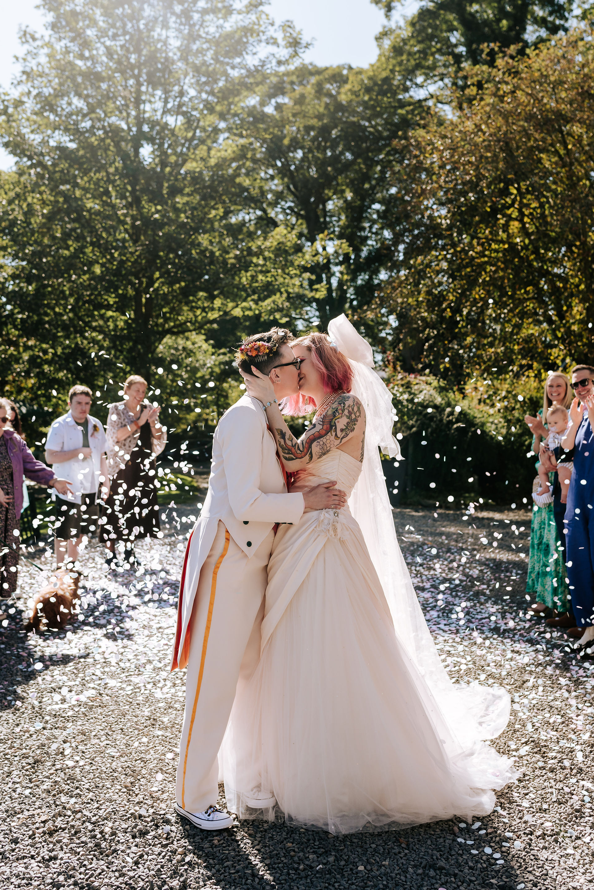 Newlyweds kissing whilst guests throw confetti 