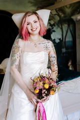 Bride posing with her bouquet wearing a wedding dress and large bow veil