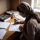 A student at a desk analysing development data, marking up a line graph headed Access to Clean Water. An international development textbook lies closed beside the chart.