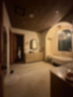 Rustic bathroom with arched niche and wood ceiling