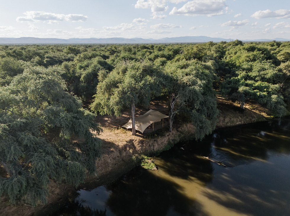 A Kutali Camp guest tent nestled in a forest overlooking a river
