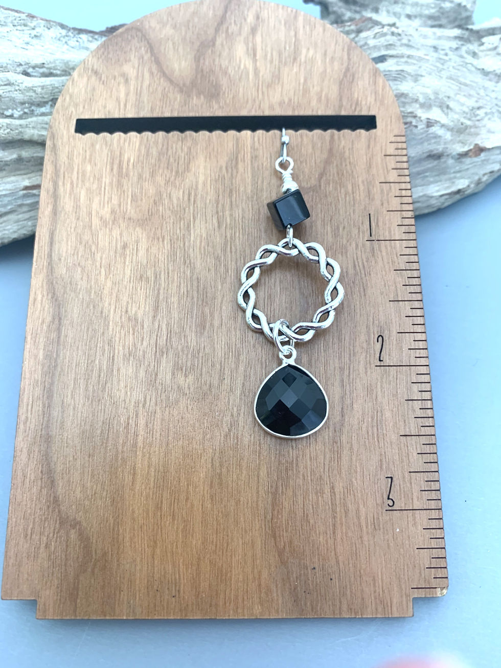 Thumbnail: Silver earring with black faceted gem on wooden display
