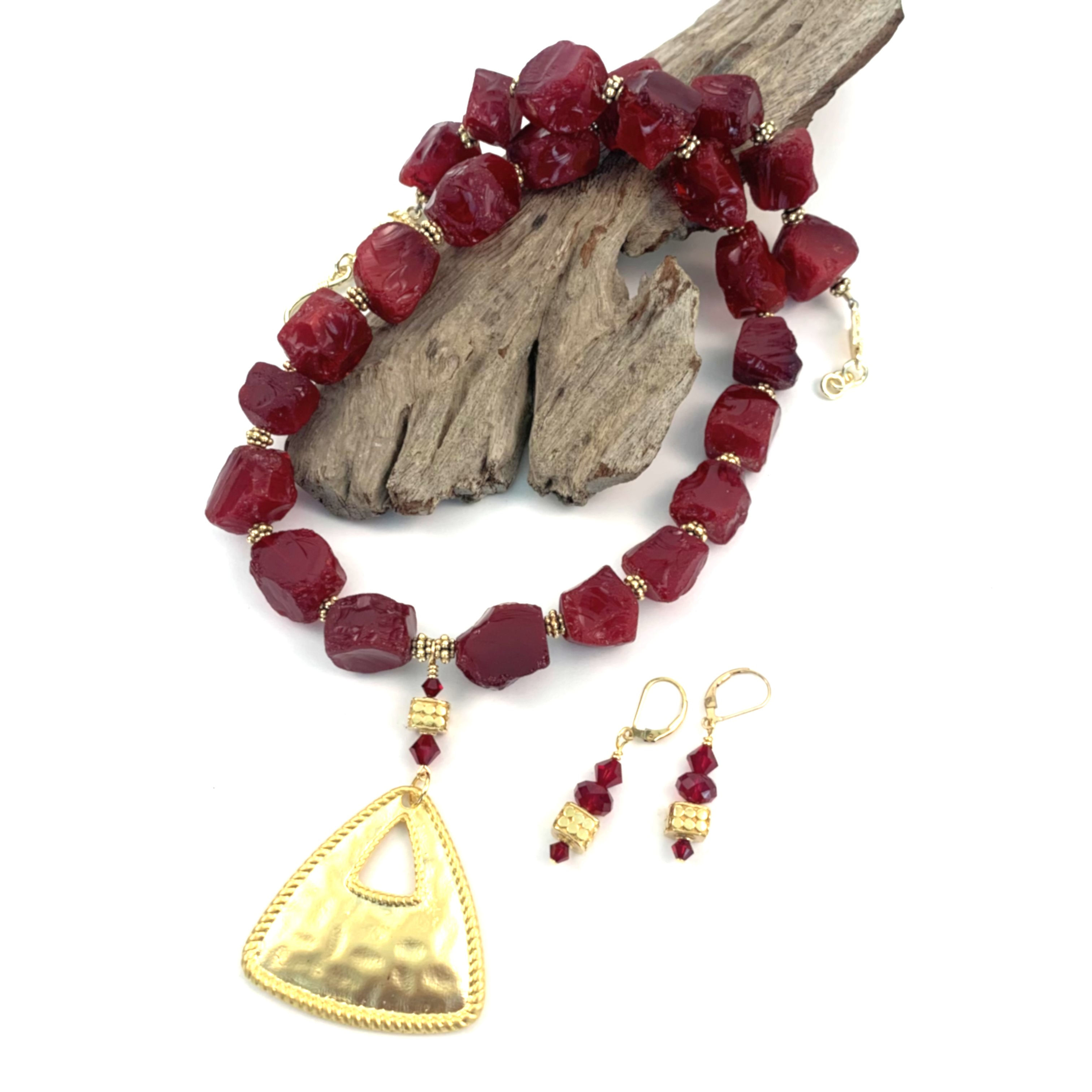 A red chunky glass beaded necklace with gold-tone spacers and pendant with a pair of matching dangle earrings.