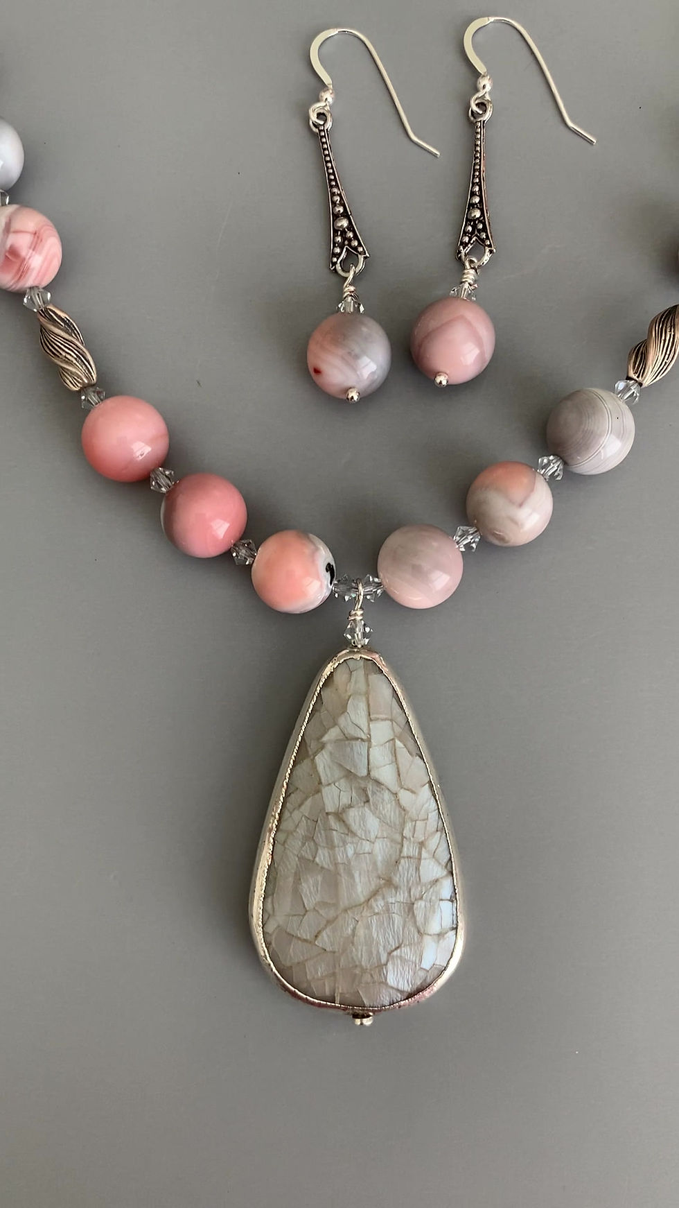 Thumbnail: A video of a handcrafted pink botswana agate necklace with gray pendant