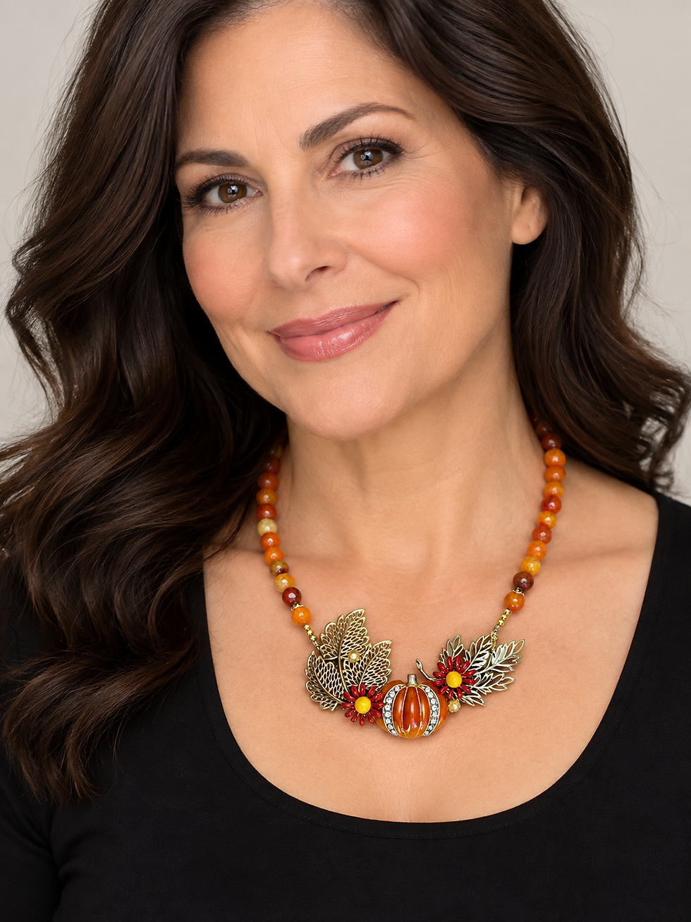 Image of an orange fall necklace on a female model with dark hair wearing a black top.