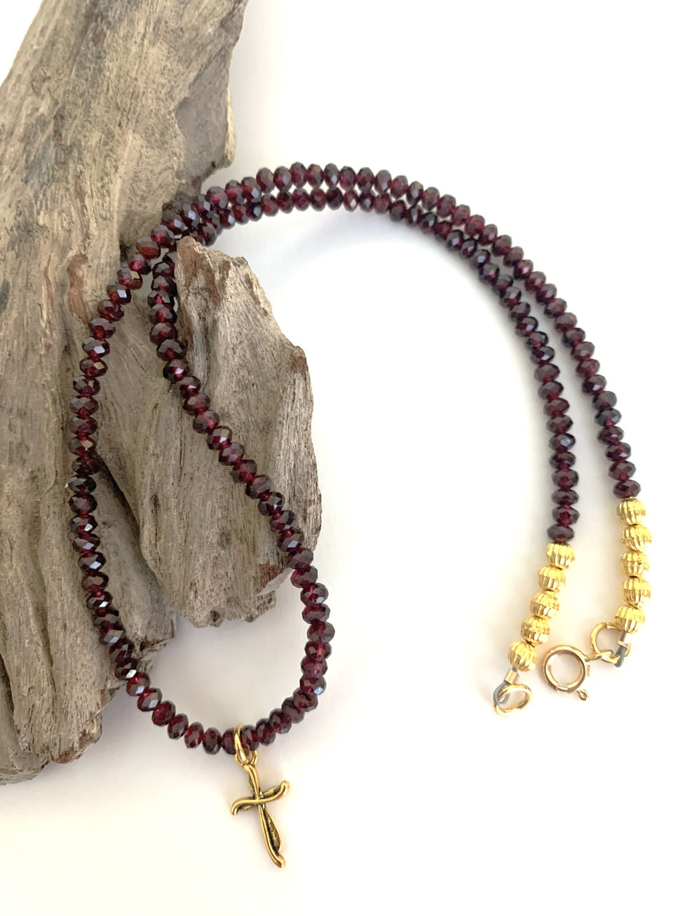 Thumbnail: Garnet gemstones with small gold cross pendant