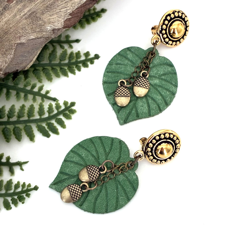 Image shows two medium green leather leaf earrings with petite acorn charms on chain.