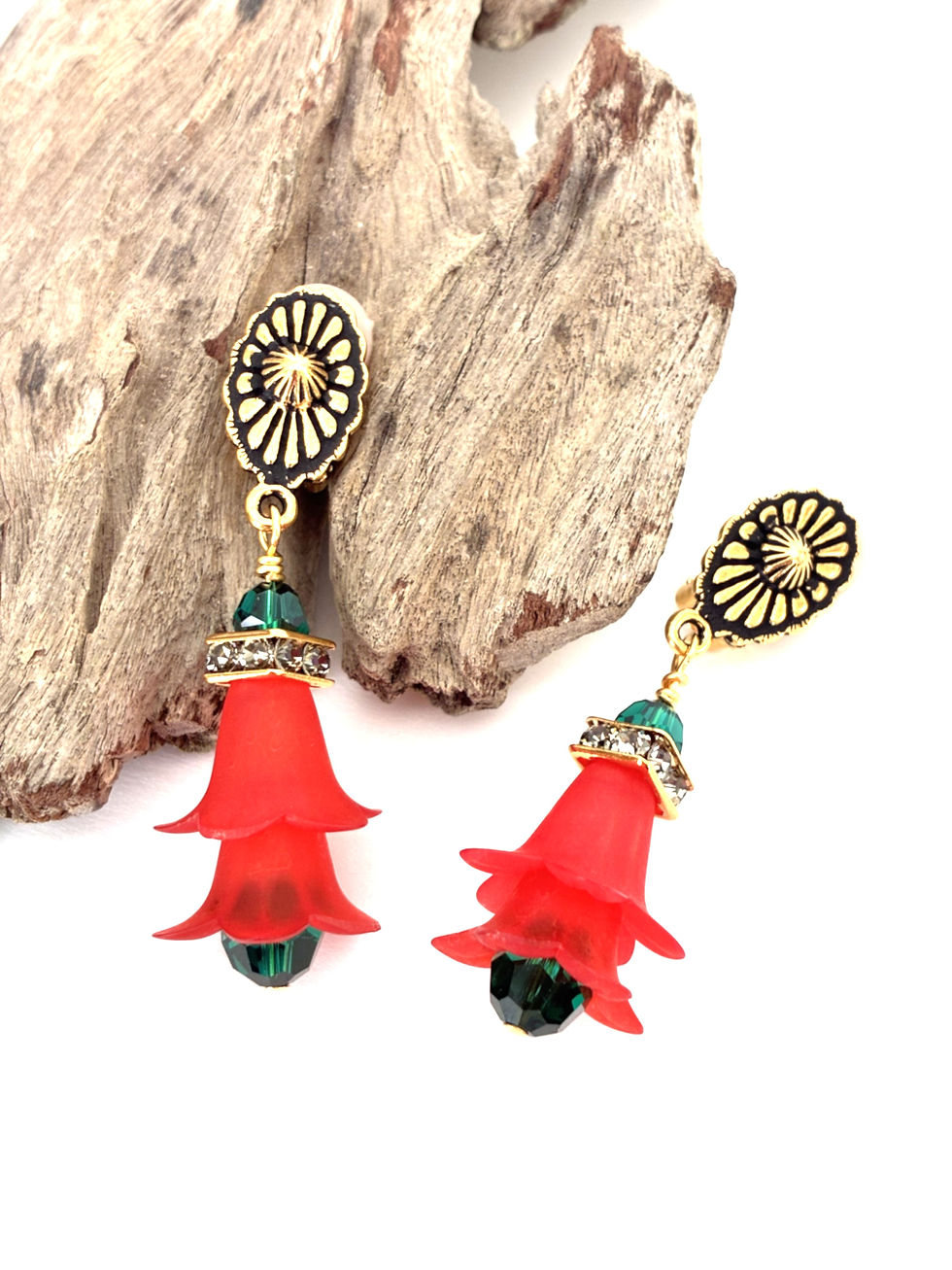 Thumbnail: Two handmade red floral earrings on a piece of wood.