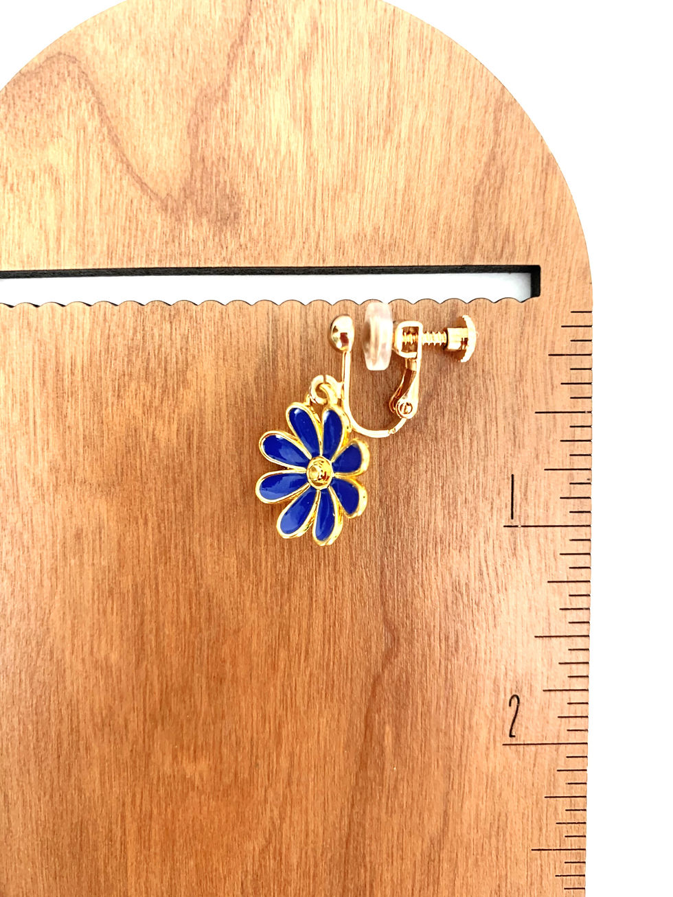 Thumbnail: Blue daisy clip-on earring on wooden display