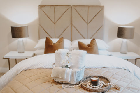 Boutique style staged bedroom for serviced accommodation with warm neutral tones and layered luxury styling.