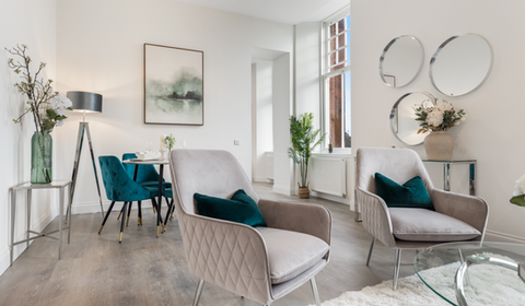 Recently staged open plan lounge diner, one of our show home projects and decorated using grey and teal velvets, with sleek chrome accents. Matching artwork and a chrome console and mirror gallery as a focal point.