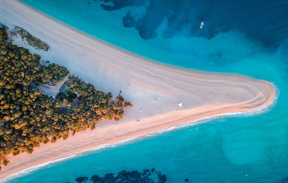 Aerial view of Zlatni Rat beach in Bol, Croatia, with turquoise water and shifting golden sand.