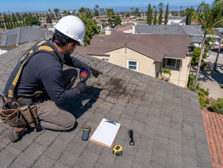 Professional roof inspector in Los Angeles using a thermal camera to detect water damage on an shingle roof.