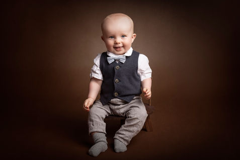 Babyfotografering. En glad dreng i flot tøj