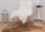 a chair with a white sheepskin cover and a brown sheepskin rug