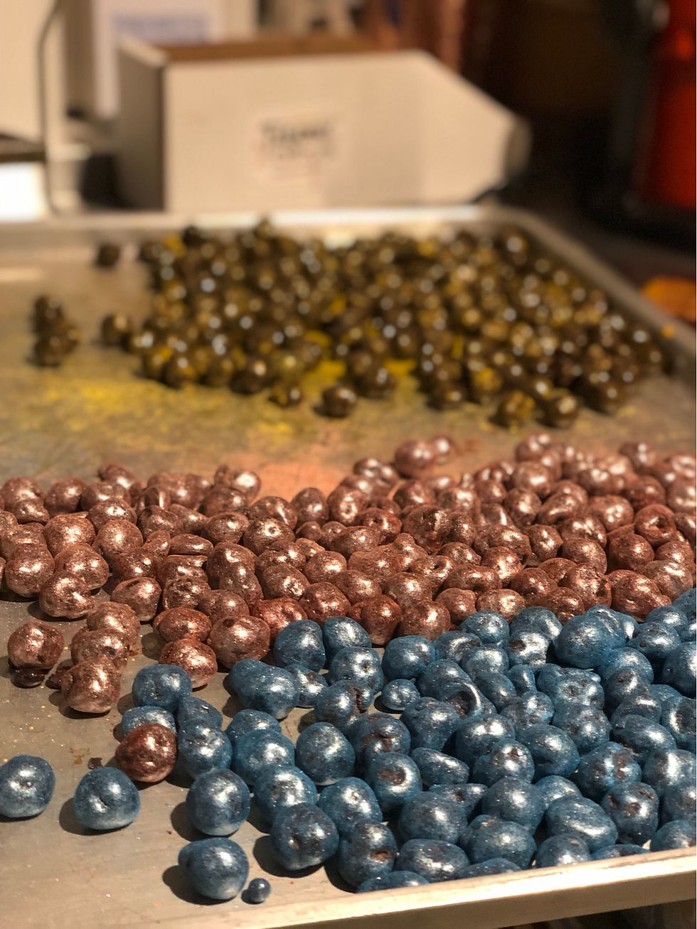 Thumbnail: a sheet tray of different colors of chocolate covered hazelnuts, showing the process of coloring the confections