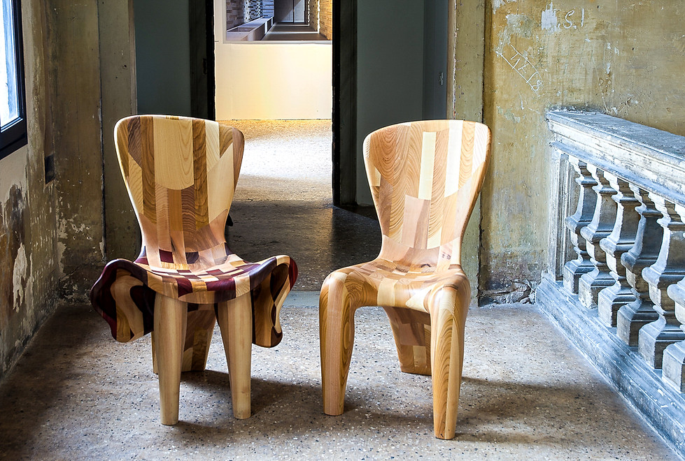 'The Chairs in Love,' by Beatriz Gerenstein presented at Time Space Existence during the 15th Venice Architecture Biennale. Two sculptural chairs crafted from exotic woods evoke feminine and masculine figures in dialogue, symbolizing love, companionship, human connection, and the relationship between art, design, and architecture.