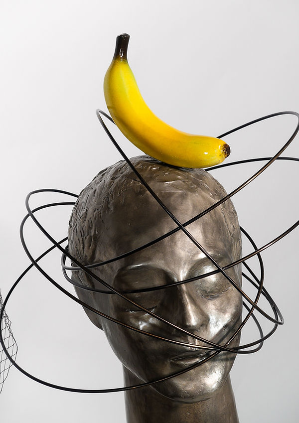 Us, bronze sculpture by Beatriz Gerenstein depicting a young woman wearing a veil and flowers beside a young man surrounded by orbital rings and a banana. The contemporary artwork explores feminine and masculine identity, human relationships, attraction, and symbolic thought.
