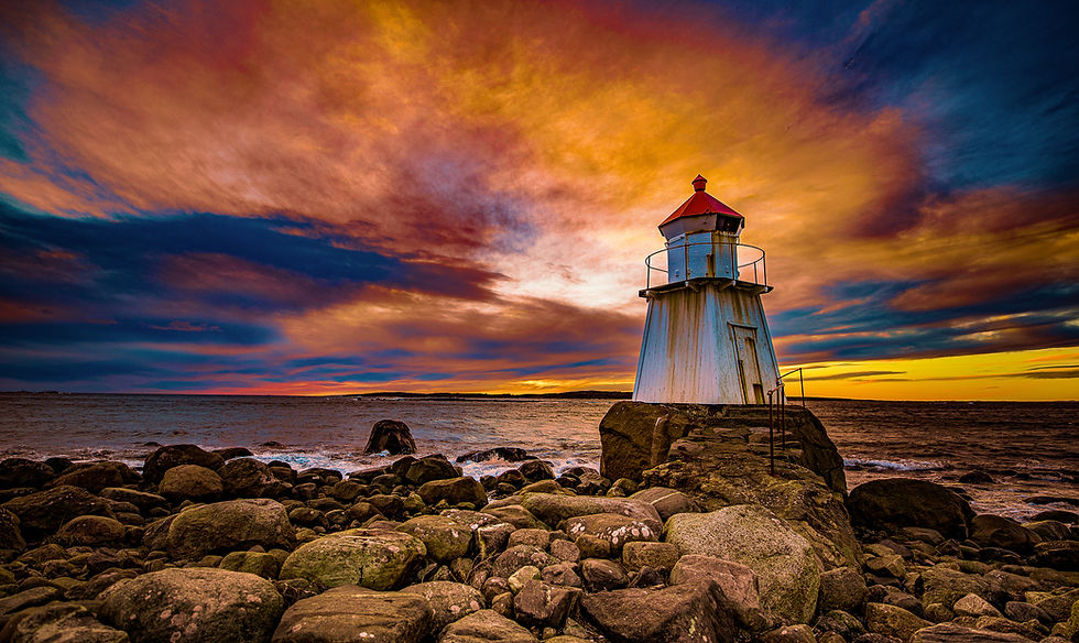 Fyr på stein ved havet, himmel med farger. Saltstraumen Bodø i bakgrunnen.