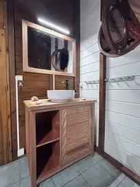 Meuble-vasque en bois, vasque blanche, miroir éclairé dans salle de bain moderne.