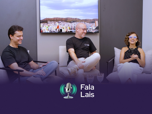 Três pessoas conversando e sorrindo, sentadas em poltronas em um ambiente moderno e descontraído, com uma televisão exibindo uma vista panorâmica de uma cidade ao fundo. Na parte inferior, há um logotipo de podcast com o texto 'Fala Lais' e um ícone de microfone.