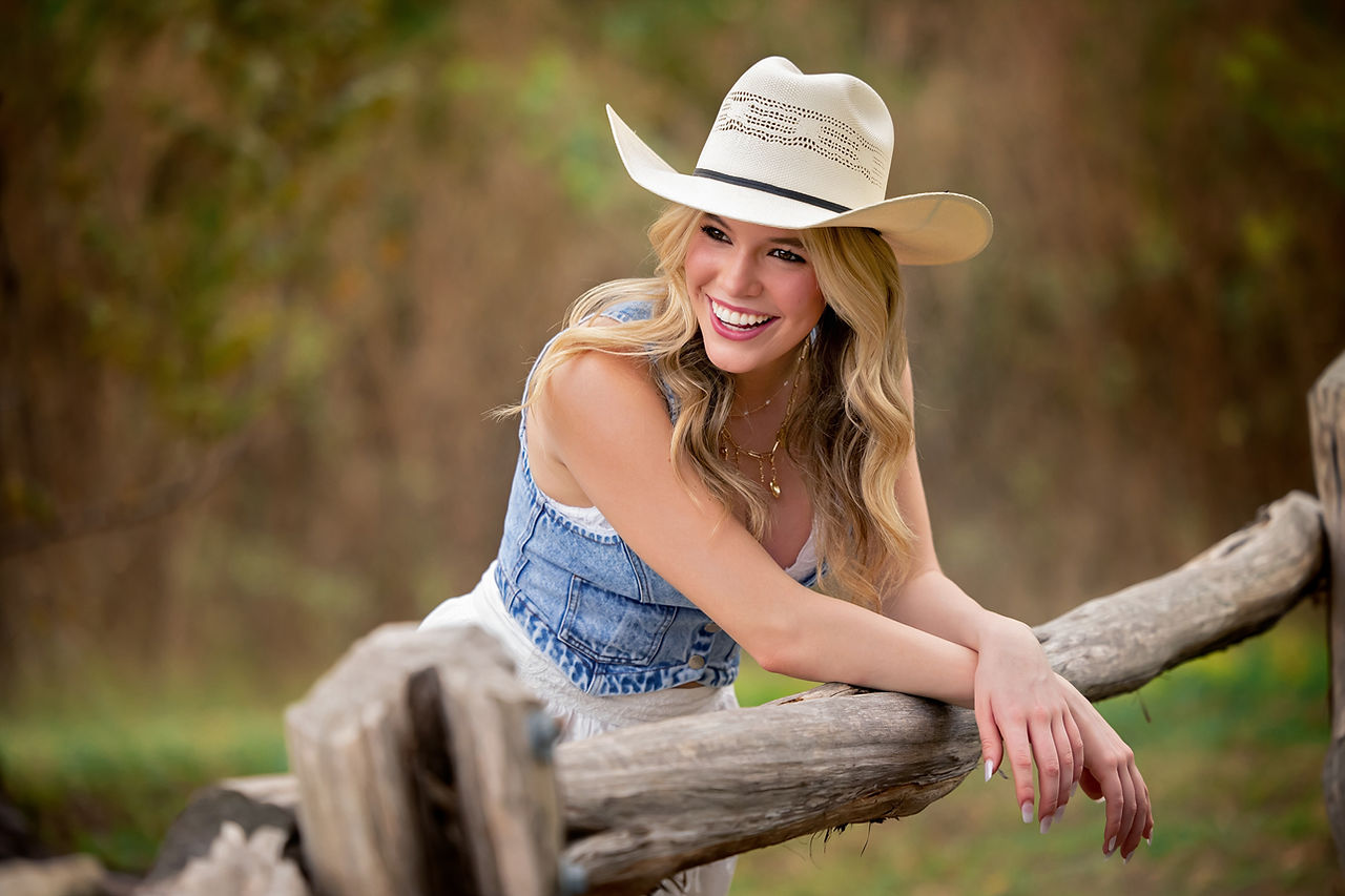 High school girl posing in a natural outdoor setting with sunset glow cowgirl hat