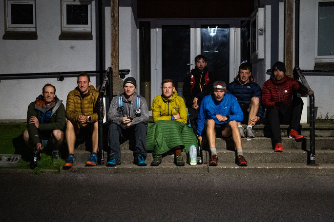 alt=“Robin Downie and support runners sitting on steps at the end of The Martin Moran Round, captured during the filming of the Martin Moran Round, a Mountain Equipment film produced by JHP Visuals"