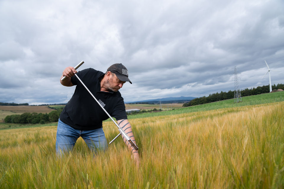 alt=“Man sampling soil in a field, captured by JHP Visuals during a film production for UNDO highlighting the environmental benefits of rock weathering"