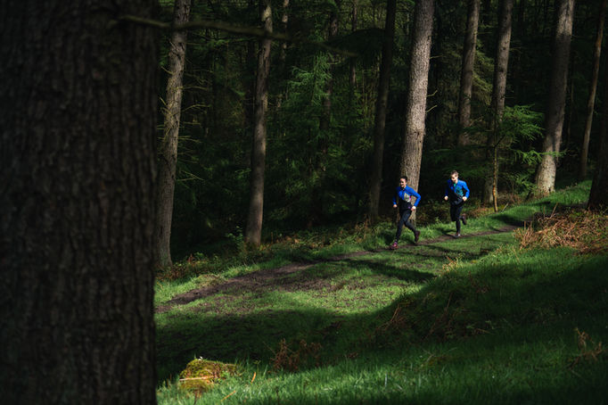 alt=“trail runners captured in a forest in the Peak District during a still and video campaign for their Tech Gore-Tex Windstopper Jacket, filmed by JHP Visuals"