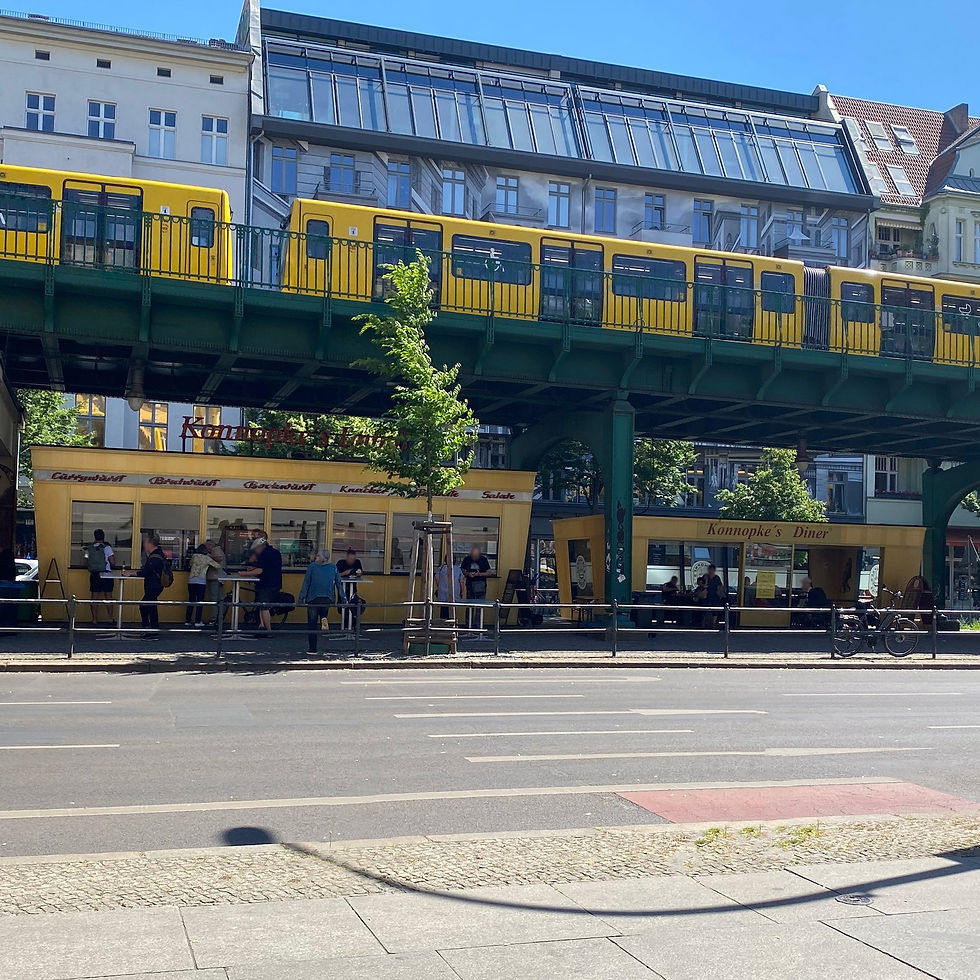 A yellow U2 train crossing the viaduct above the Konnopke sausage stand on Schoenhauser Allee