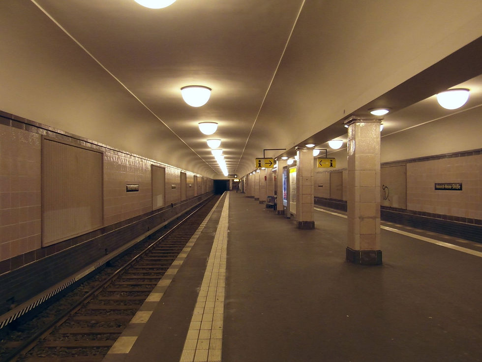 The empty platform at Heinrich-Heine-Straße U-Bahn station on the U8, lit by warm ceiling lamps
