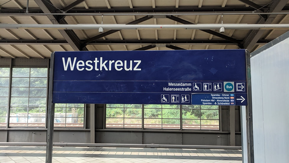 The Westkreuz S-Bahn name sign, a white name on a blue board, under the station's steel roof