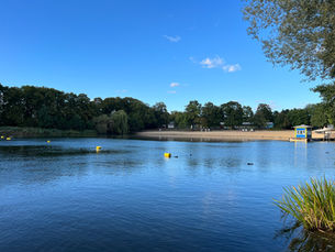 The beach and buoyed swimming area at Strandbad Orankesee in Lichtenberg under a wide blue sky in mid-September