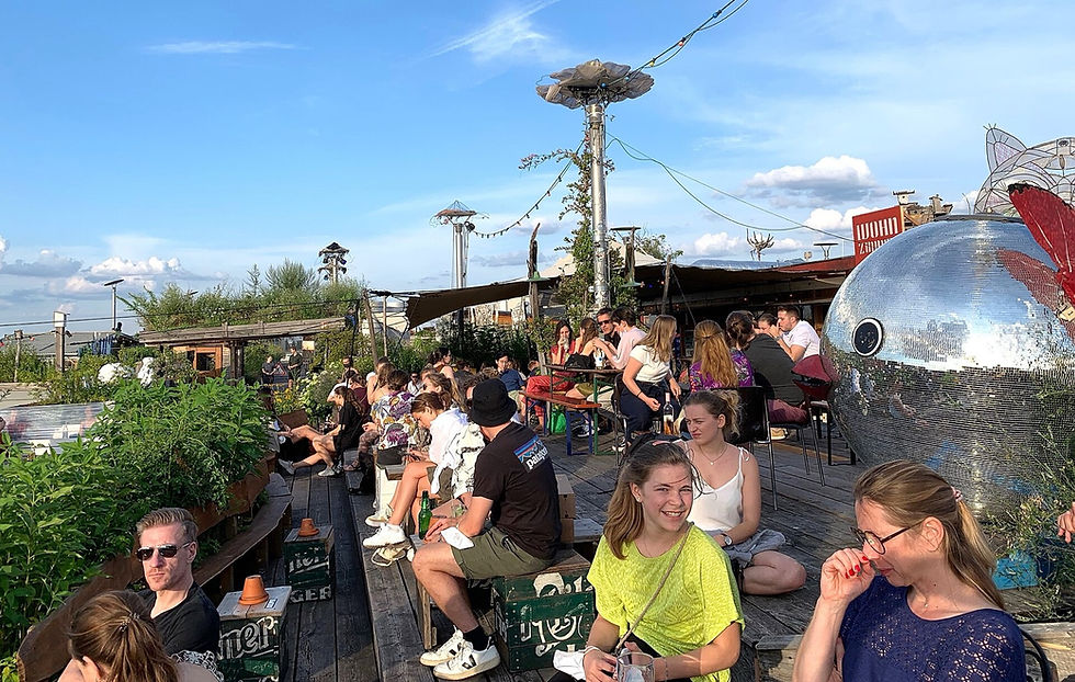 People at the Klunkerkranich rooftop bar and garden above Karl-Marx-Straße in Neukölln at sunset