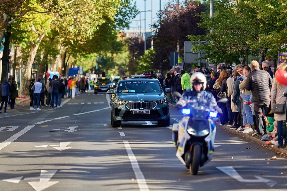 A police motorcycle and race safety car leading the marathon up an empty Rheinstraße, with spectators already on the pavement