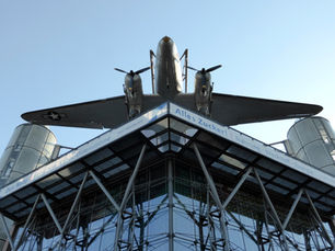 The Douglas C-47 Rosinenbomber mounted on the roof of the Deutsches Technikmuseum's glass New Building