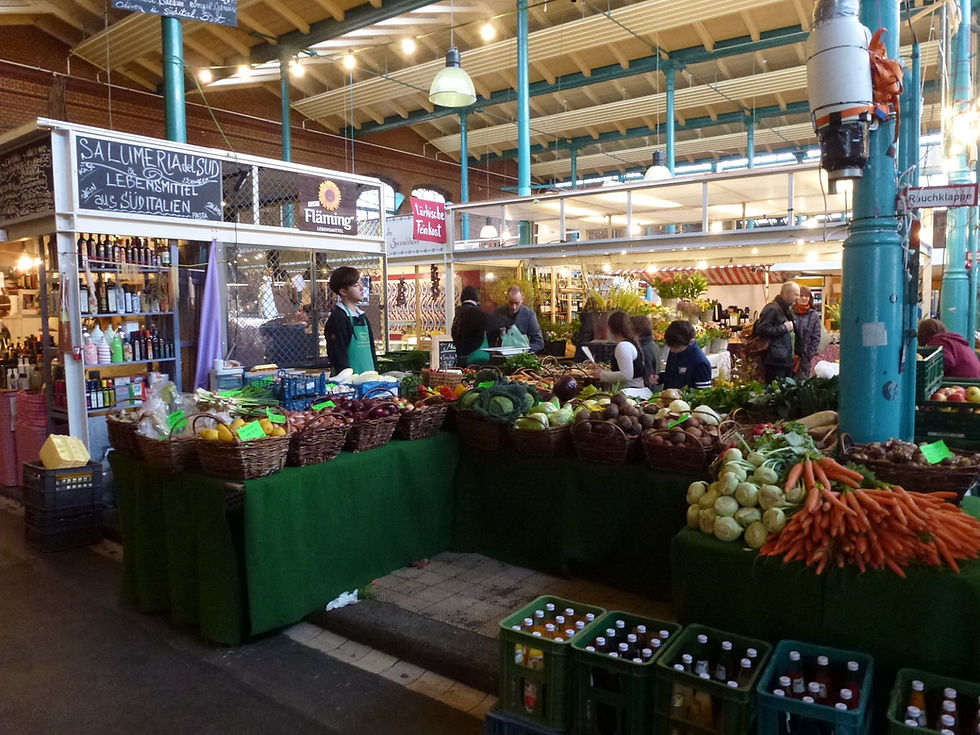 A produce and Italian deli stall at Markthalle Neun on a market day, next to one of the green cast-iron columns