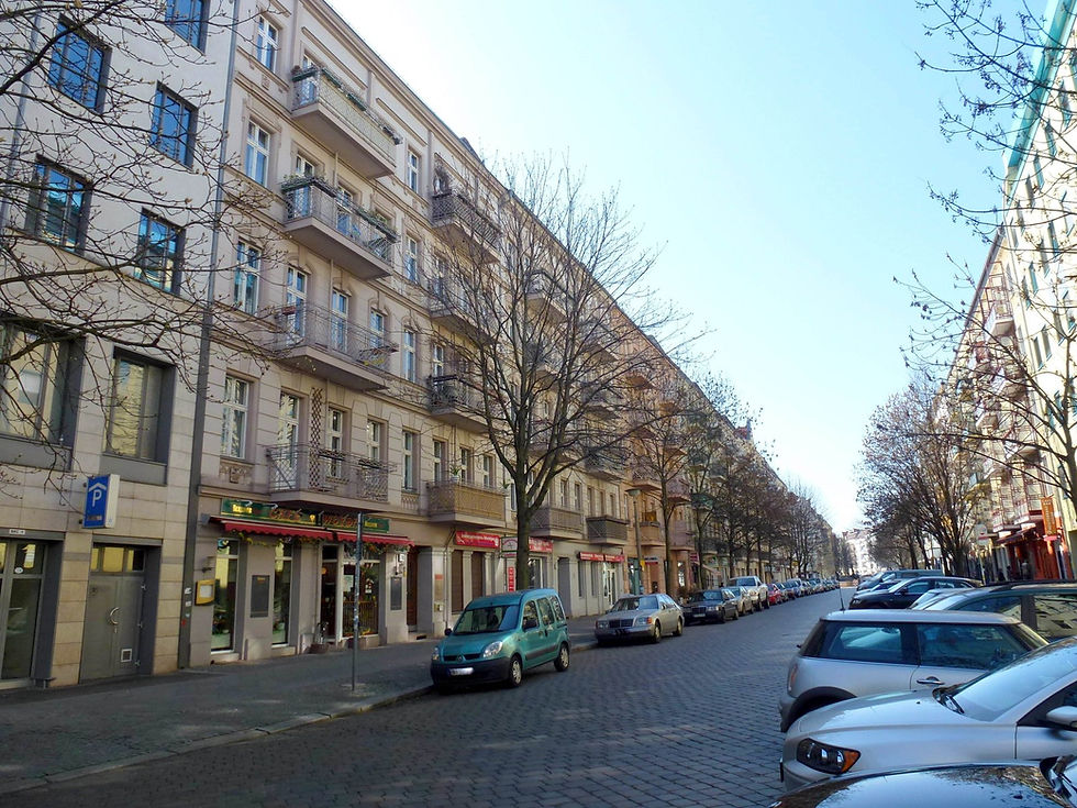 A Berlin residential street in Prenzlauer Berg with cars parked along both kerbs under bare plane trees